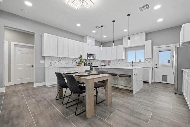 kitchen with white cabinetry, decorative light fixtures, stainless steel appliances, and a center island