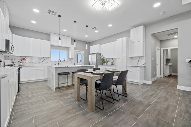 kitchen featuring white cabinetry, pendant lighting, a kitchen island, and appliances with stainless steel finishes