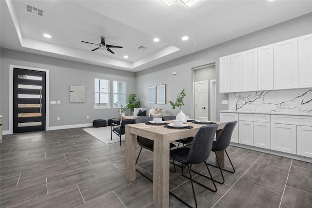 dining room featuring a raised ceiling and ceiling fan