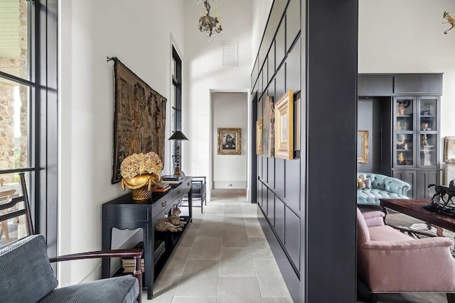 hallway featuring light tile patterned floors and a high ceiling