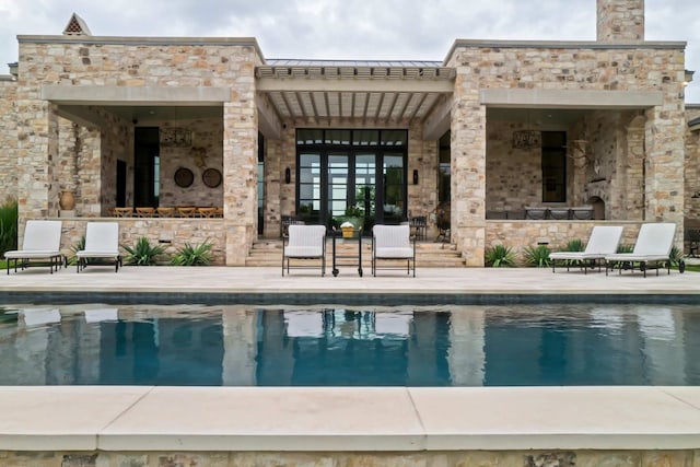 back of house featuring a standing seam roof, a patio, a fireplace, an outdoor pool, and metal roof