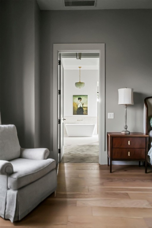 sitting room with visible vents, wood finished floors, and ornamental molding