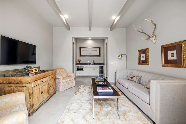 living room featuring wine cooler, beam ceiling, and finished concrete flooring