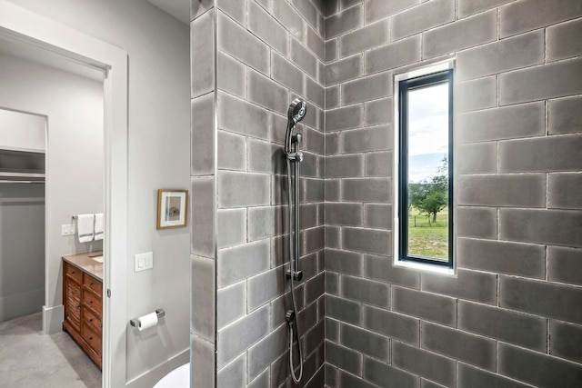 full bathroom featuring a tile shower, plenty of natural light, and vanity