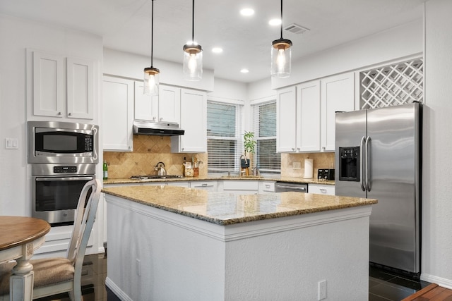 6136 Oliver Loving Trl, Austin, TX 78749 - kitchen featuring stainless steel appliances, under cabinet range hood, a kitchen island, white cabinetry, and light stone countertops