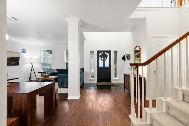 foyer entrance with decorative columns, wood-type flooring, and crown molding