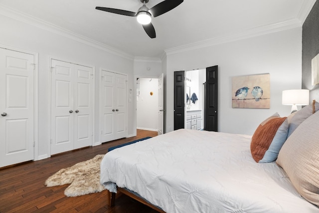 bedroom featuring ensuite bath, ornamental molding, dark hardwood / wood-style floors, and two closets