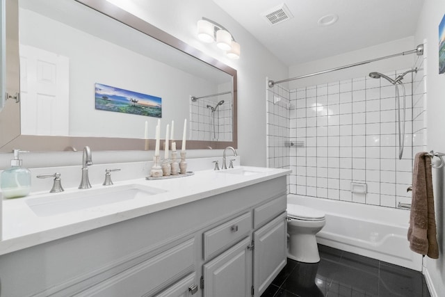 full bathroom with tile patterned flooring, vanity, tiled shower / bath, and toilet