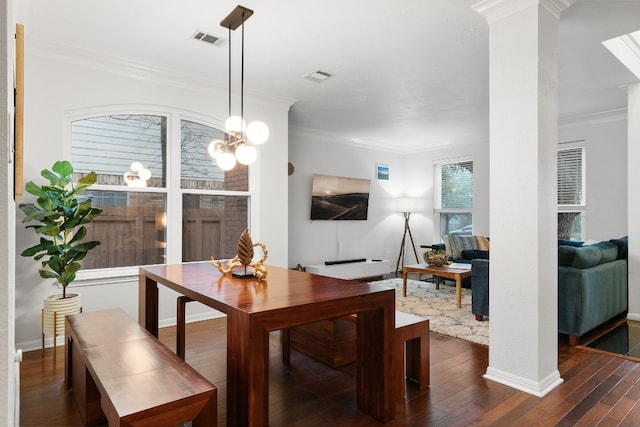 dining area with a notable chandelier, crown molding, dark hardwood / wood-style floors, and ornate columns