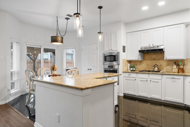 kitchen featuring white cabinetry, hanging light fixtures, light stone countertops, and a kitchen island