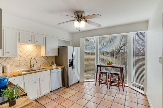 kitchen with sink, appliances with stainless steel finishes, white cabinetry, light tile patterned flooring, and decorative backsplash