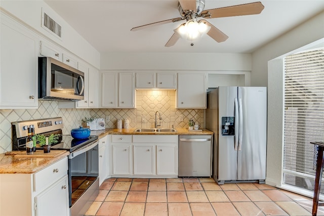 kitchen with sink, tasteful backsplash, light tile patterned floors, appliances with stainless steel finishes, and white cabinets