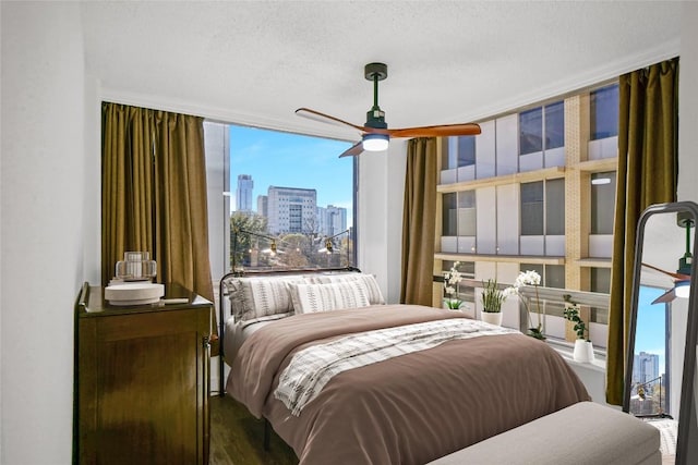 bedroom featuring expansive windows, wood-type flooring, ceiling fan, and a textured ceiling