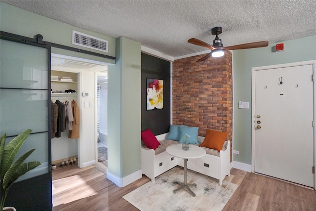 entryway with ceiling fan, light hardwood / wood-style floors, a barn door, and a textured ceiling