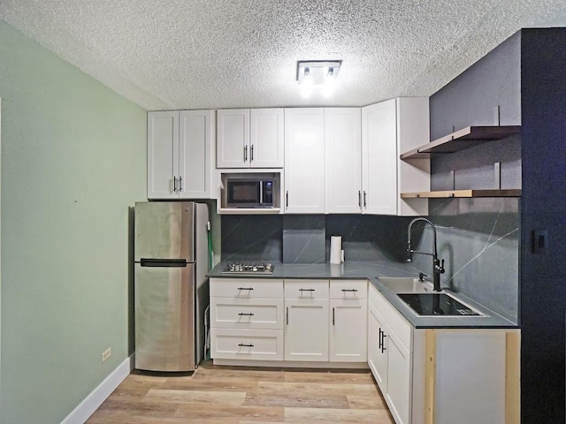 kitchen with stainless steel refrigerator, white cabinets, and built in microwave