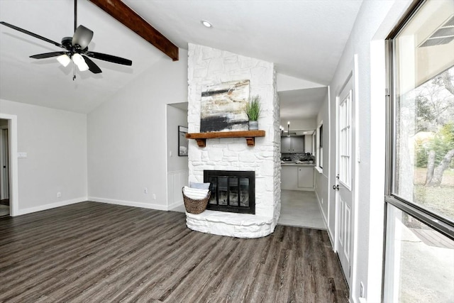 unfurnished living room featuring dark hardwood / wood-style flooring, vaulted ceiling with beams, a stone fireplace, and ceiling fan