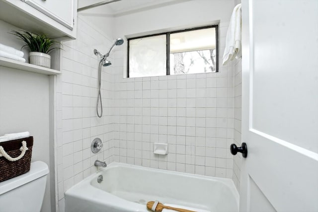 bathroom featuring tiled shower / bath combo and toilet