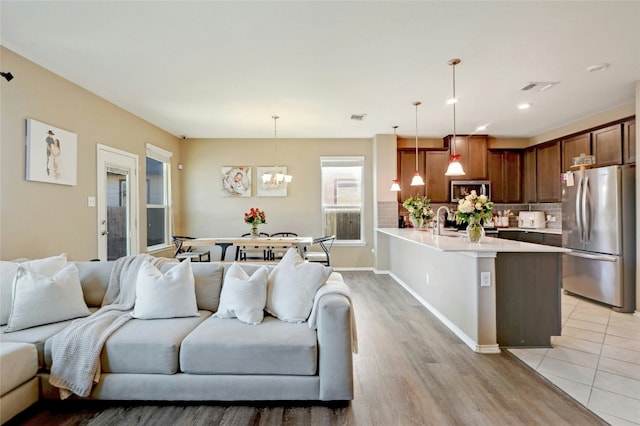 living room with a notable chandelier, light hardwood / wood-style flooring, and sink