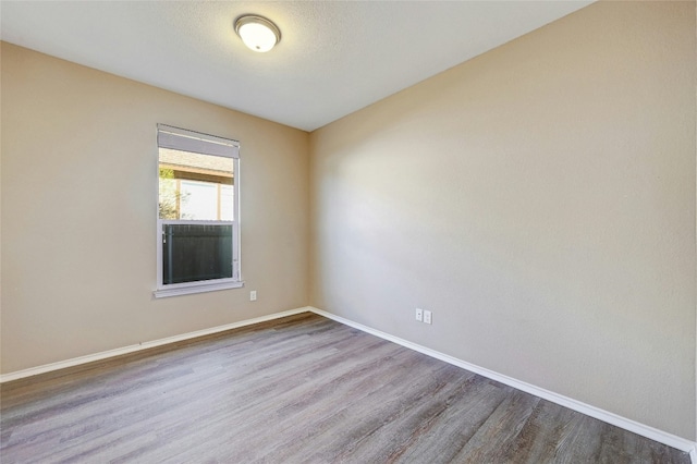 unfurnished room with hardwood / wood-style flooring and a textured ceiling