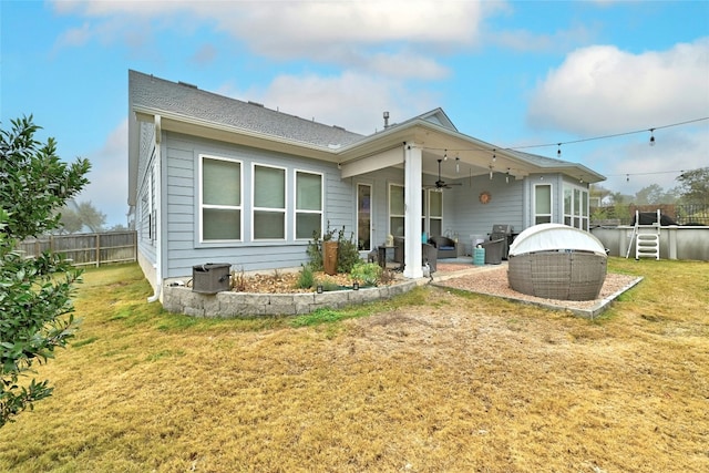 back of property with a patio, a swimming pool, a yard, and ceiling fan