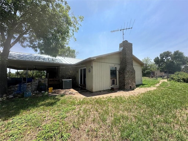 rear view of house featuring central AC unit and a lawn