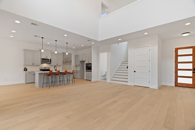 living room with a healthy amount of sunlight, sink, light hardwood / wood-style flooring, and a high ceiling