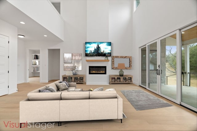 living room with hardwood / wood-style floors, a towering ceiling, and french doors