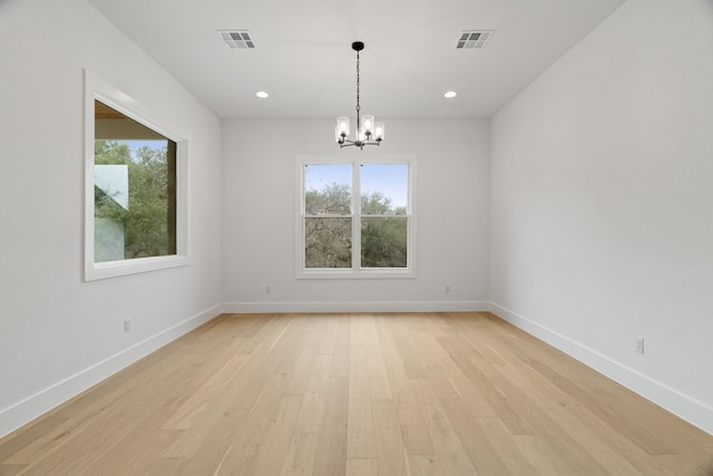 empty room featuring a notable chandelier, light hardwood / wood-style floors, and a healthy amount of sunlight