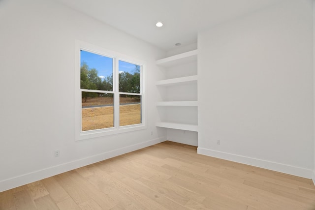 empty room with built in features and light wood-type flooring