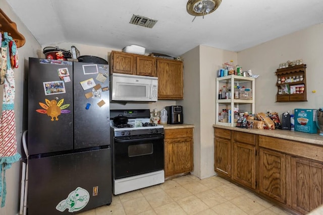 kitchen featuring vaulted ceiling, black gas range oven, and stainless steel refrigerator