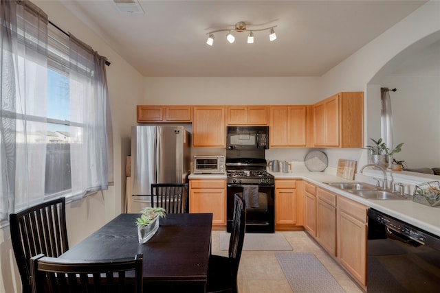 kitchen with sink, light tile patterned floors, light brown cabinetry, and black appliances