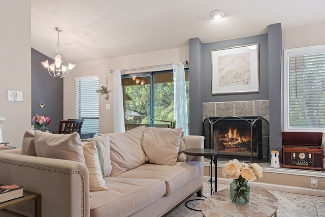 living room with a tile fireplace, vaulted ceiling, a wealth of natural light, and a notable chandelier