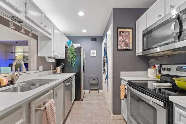 kitchen featuring light tile patterned floors, appliances with stainless steel finishes, sink, and white cabinets