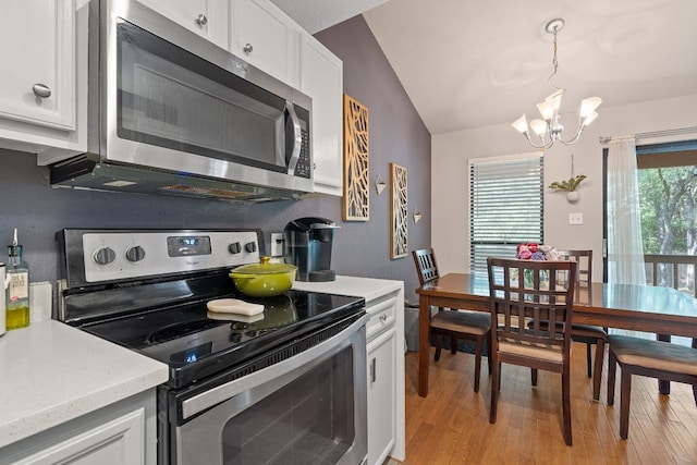 kitchen featuring pendant lighting, lofted ceiling, white cabinets, a chandelier, and stainless steel appliances