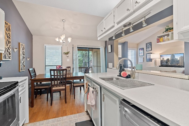 kitchen featuring lofted ceiling, sink, decorative light fixtures, stainless steel appliances, and white cabinets