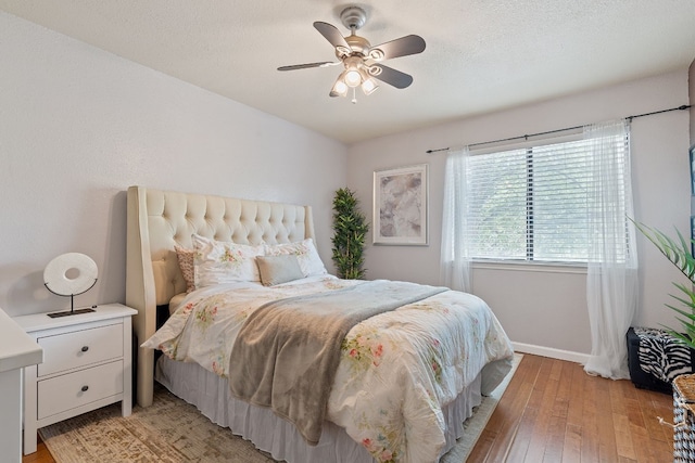 bedroom with ceiling fan, light hardwood / wood-style flooring, and a textured ceiling