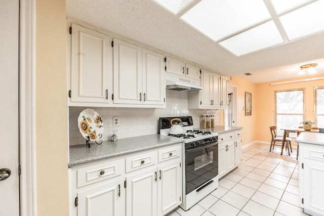 kitchen with tasteful backsplash, white gas range, white cabinets, light tile patterned floors, and a textured ceiling