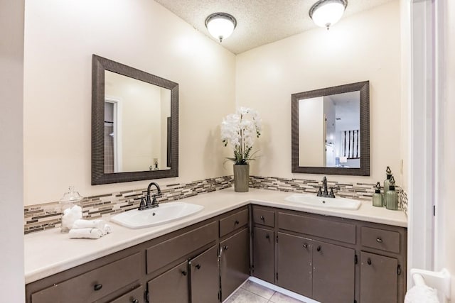 bathroom with tile patterned floors, vanity, a textured ceiling, and backsplash