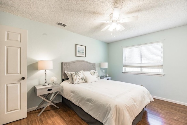 bedroom featuring ceiling fan, dark hardwood / wood-style floors, and a textured ceiling