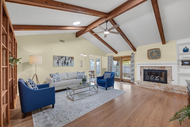 living room featuring lofted ceiling with beams, hardwood / wood-style flooring, ceiling fan, a textured ceiling, and built in shelves