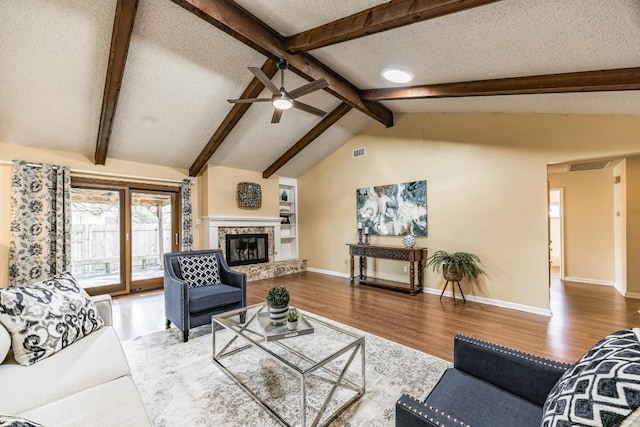 living room with lofted ceiling with beams, ceiling fan, hardwood / wood-style floors, and a textured ceiling