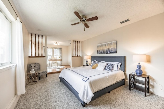 carpeted bedroom with ceiling fan and a textured ceiling