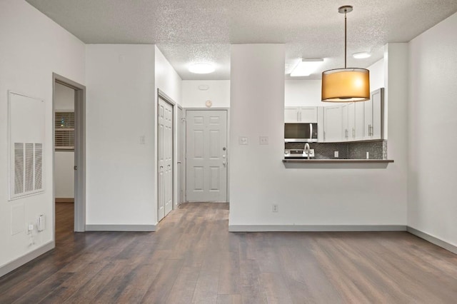 unfurnished living room with dark wood-type flooring and a textured ceiling