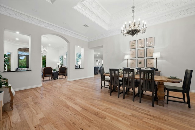 dining room featuring an inviting chandelier, a tray ceiling, crown molding, and light wood-type flooring