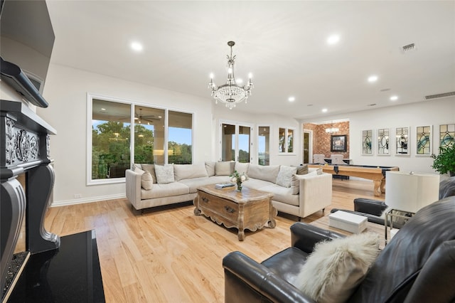 living room featuring an inviting chandelier, pool table, and light hardwood / wood-style flooring