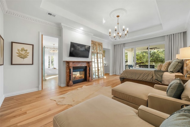 bedroom featuring a multi sided fireplace, access to exterior, a raised ceiling, and multiple windows