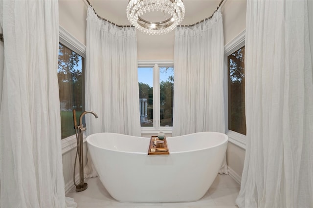 bathroom with a notable chandelier, tile patterned floors, and a tub