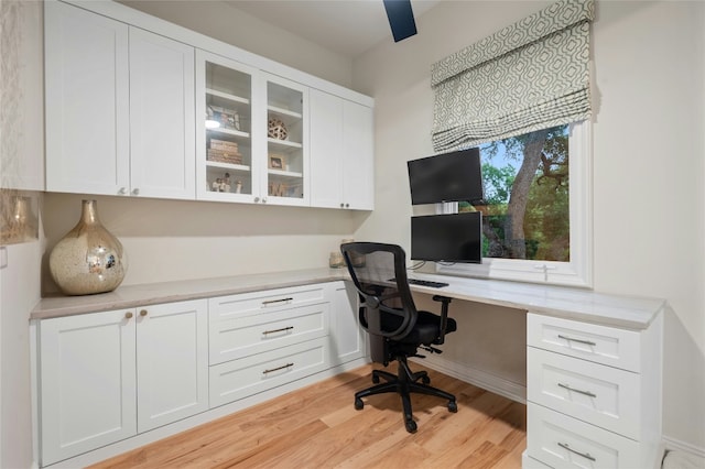 home office with built in desk and light wood-type flooring