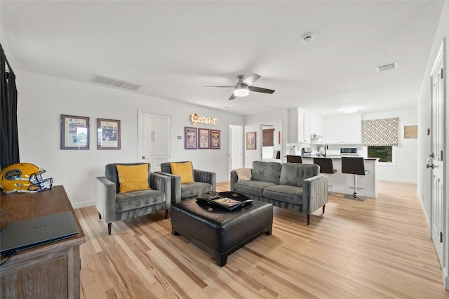 living room with sink, light hardwood / wood-style flooring, and ceiling fan