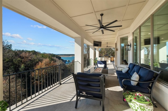 view of patio / terrace with a water view, an outdoor living space with a fire pit, and ceiling fan